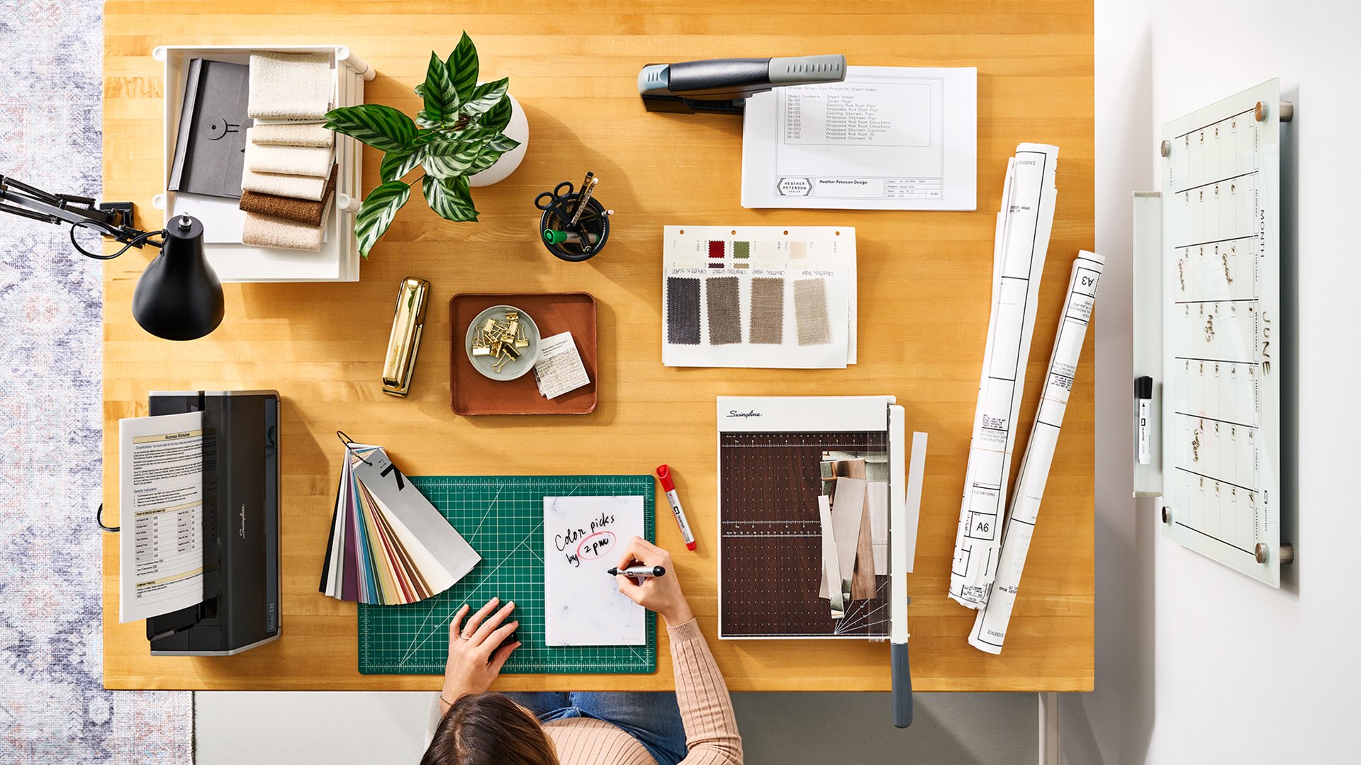Clean desk with a woman writing on a Quartet notepad